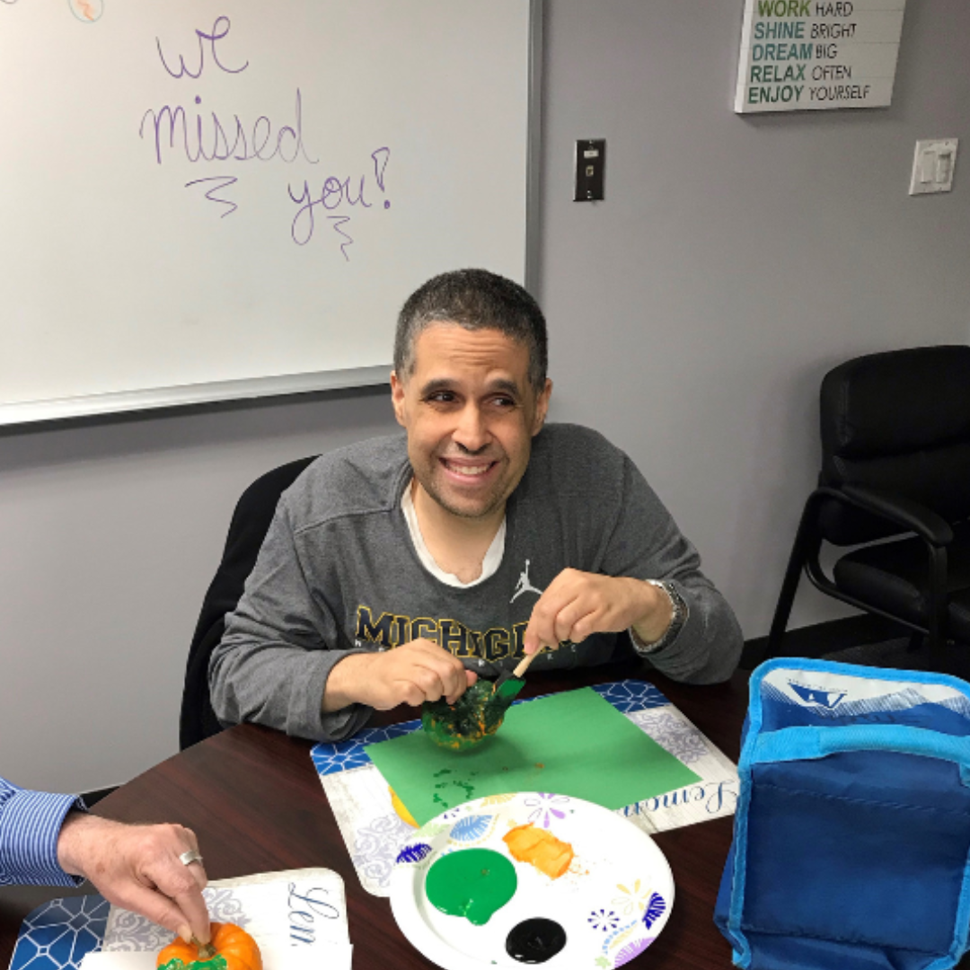 Adult man enjoying making a craft at a day program. Alternatives Inc.