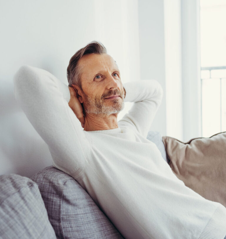 Father sitting back on couch, looking at ease. Alternatives Inc