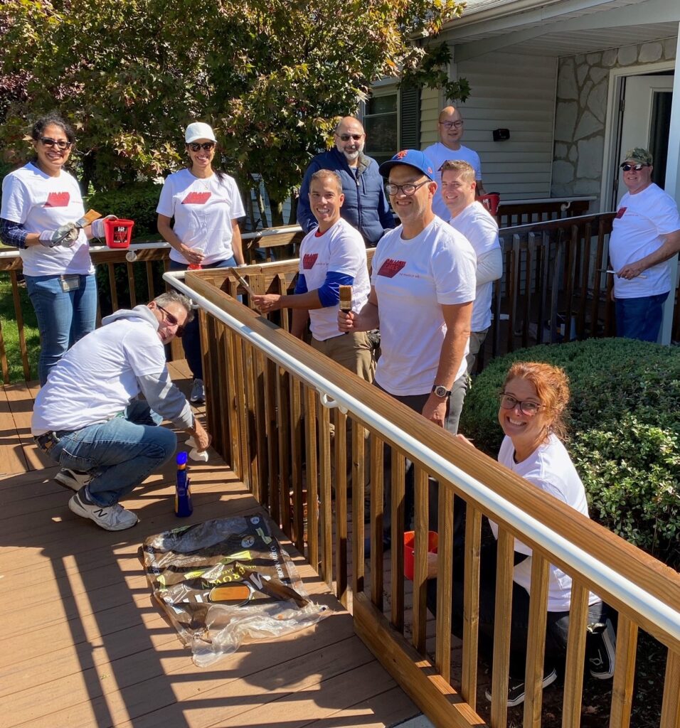 Group of volunteers planting a garden outside a home. Alternatives Inc